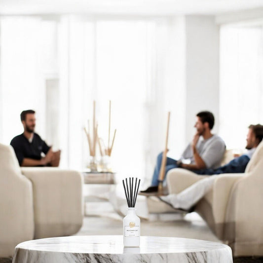 Zwei Männer im modernen Wohnzimmer mit Moonrich Duftflakon auf dem Tisch – entspannte Atmosphäre mit dezentem Duft.